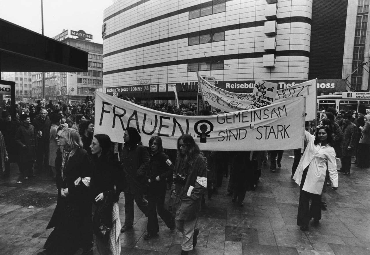 schwarz-weiss-Bild mit demonstrierenden Frauen mit großem weißem Banner in der Luft.