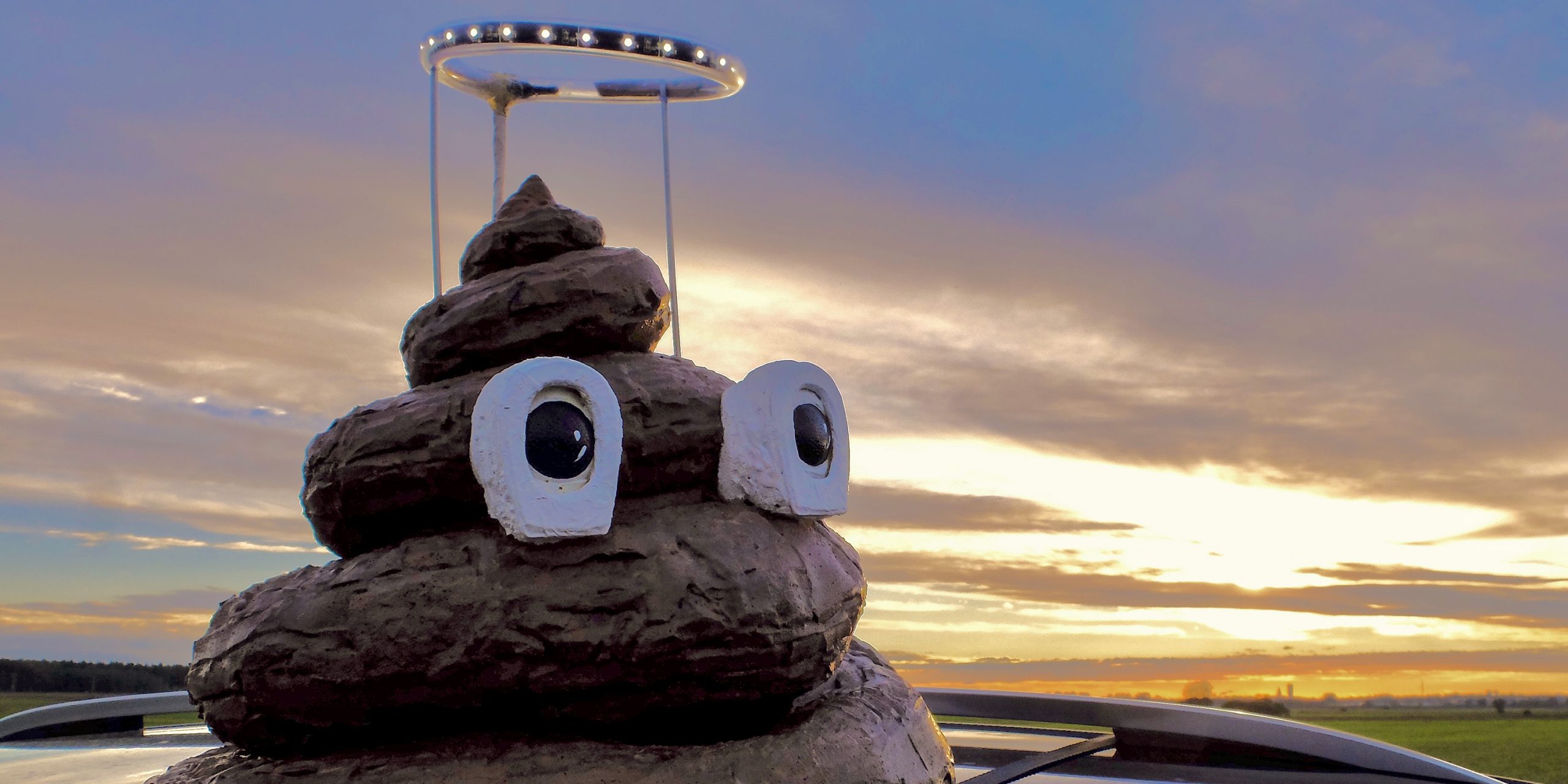Scheißhaufen mit Augen und Heiligenschein vor Sonnenuntergang
